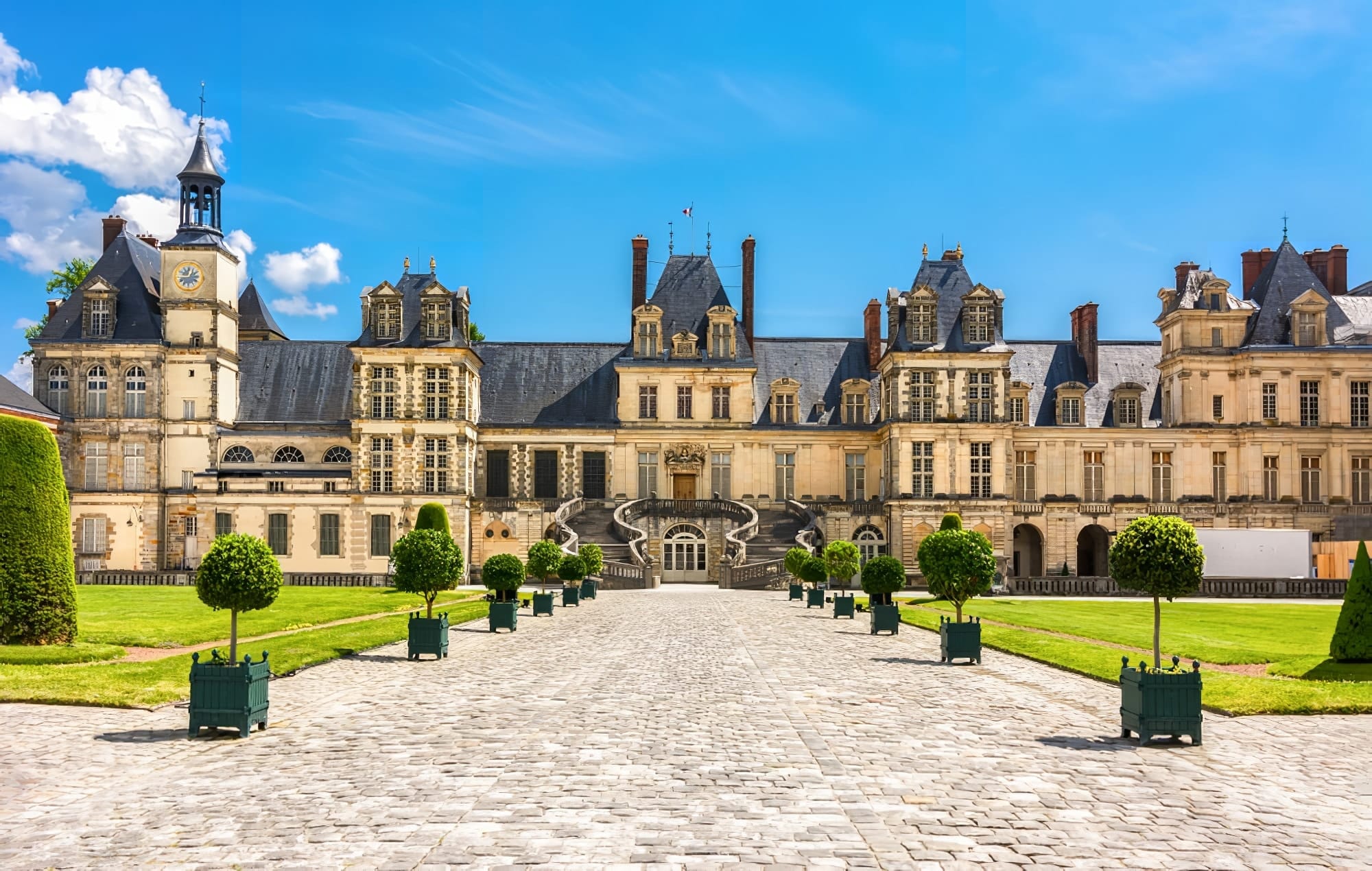 Historic Château de Fontainebleau with its elegant facade, grand staircase, and lush gardens.