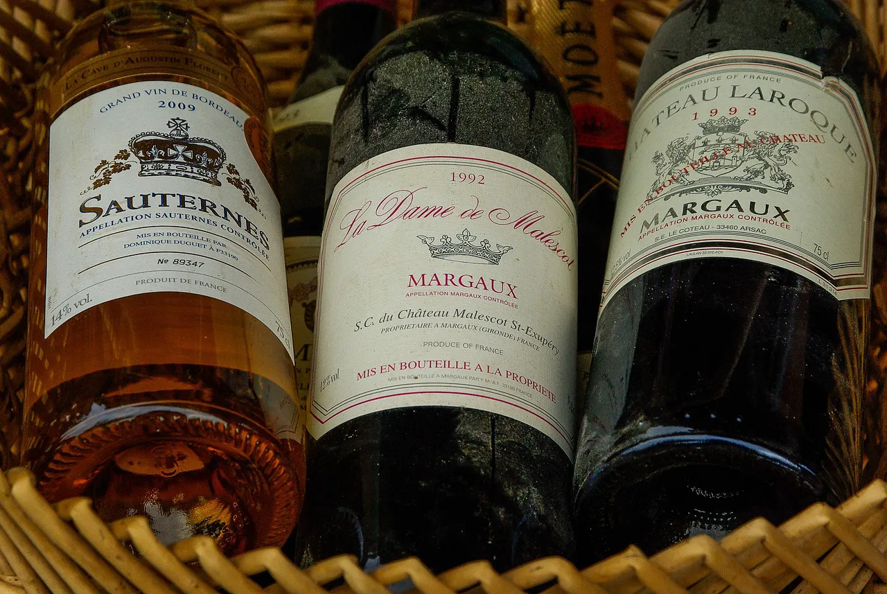 Three French wine bottles in a basket, including a white Sauternes and two red Margaux wines.