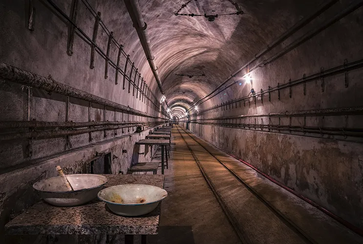 Interior view of a tunnel in the Maginot Line, with arched ceilings and dim lighting.