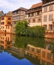Colorful timber-framed houses reflected in the canal waters of Petite France, a historic district in Strasbourg, France.