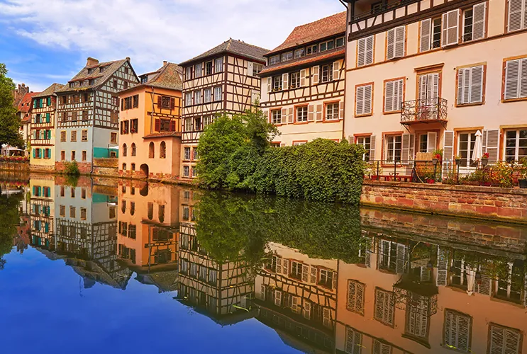 Colorful timber-framed houses reflected in the canal waters of Petite France, a historic district in Strasbourg, France.